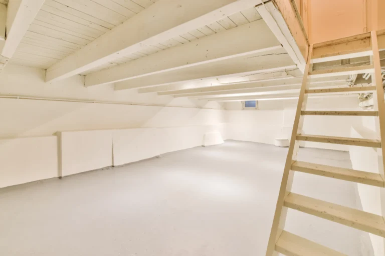 Spacious and well-lit house basement with wooden stairs.